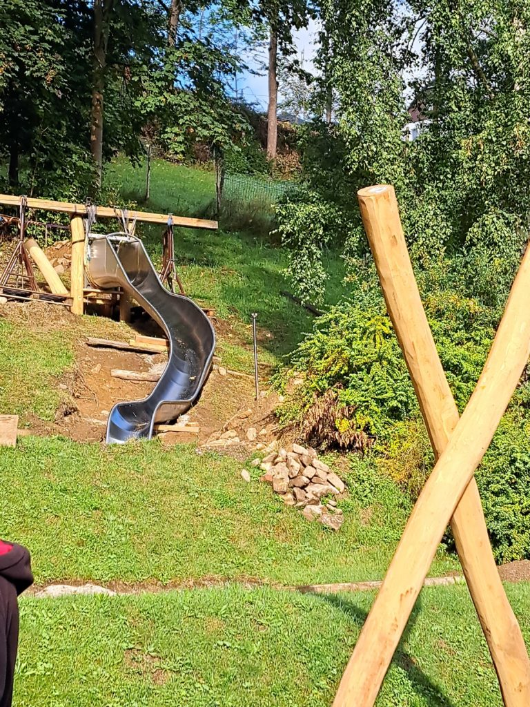 In 4 Elterneinsätzen gelang es uns, eine 7 Meter lange Rutsche, 19 Robinen Stämme mit bis zu 5 Meter Länge, einen Rutschen Aufstieg, der 7 Meter lang ist, und Tonnen von Beton und Sand mit Schubkarren und Minibagger an Ort und Stelle zu bringen.