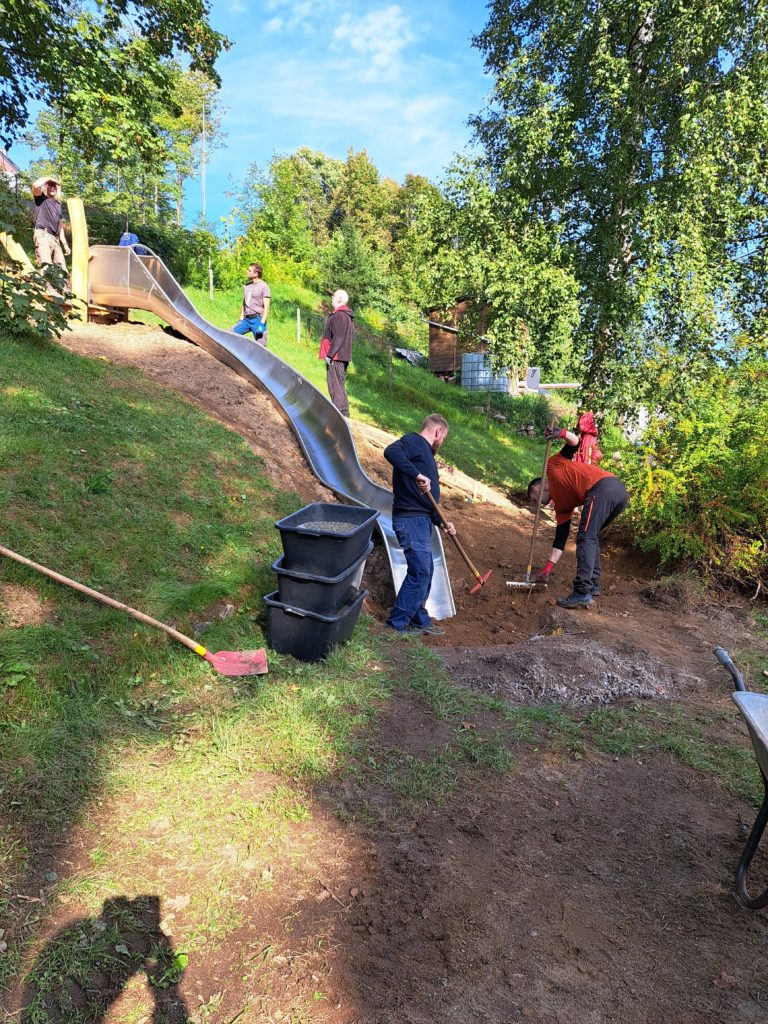 In 4 Elterneinsätzen gelang es uns, eine 7 Meter lange Rutsche, 19 Robinen Stämme mit bis zu 5 Meter Länge, einen Rutschen Aufstieg, der 7 Meter lang ist, und Tonnen von Beton und Sand mit Schubkarren und Minibagger an Ort und Stelle zu bringen.