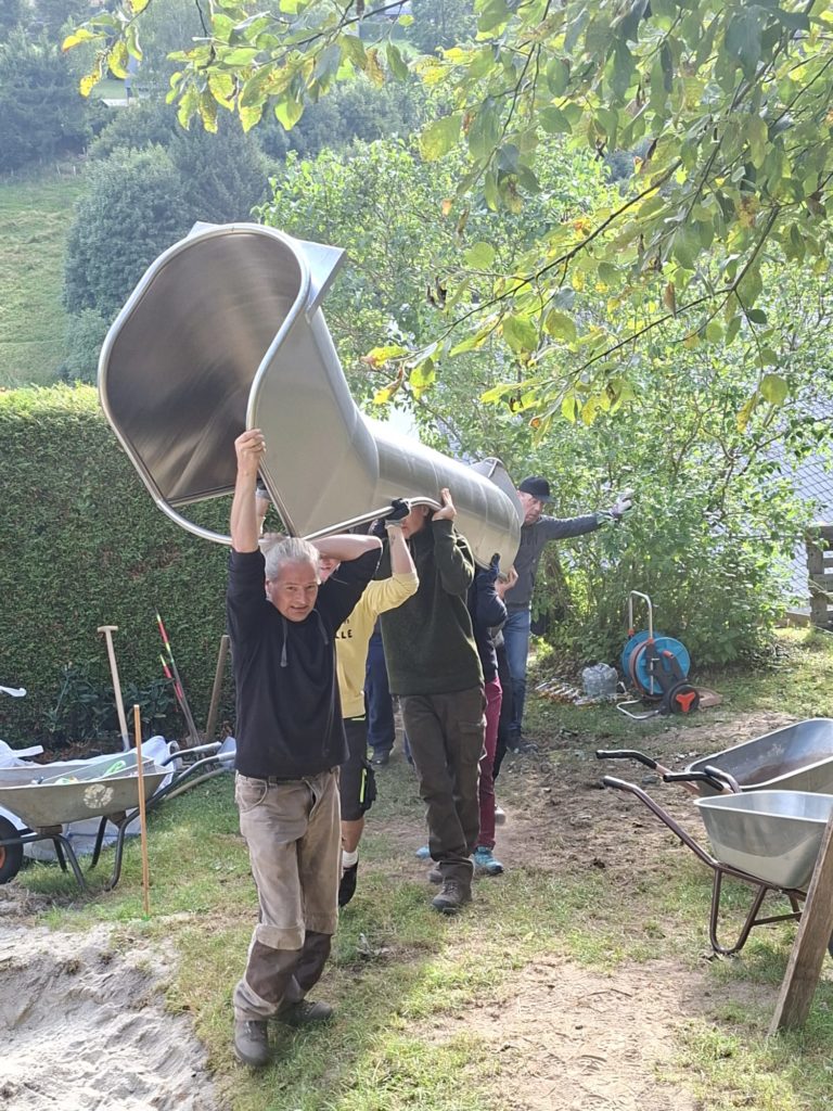 In 4 Elterneinsätzen gelang es uns, eine 7 Meter lange Rutsche, 19 Robinen Stämme mit bis zu 5 Meter Länge, einen Rutschen Aufstieg, der 7 Meter lang ist, und Tonnen von Beton und Sand mit Schubkarren und Minibagger an Ort und Stelle zu bringen.