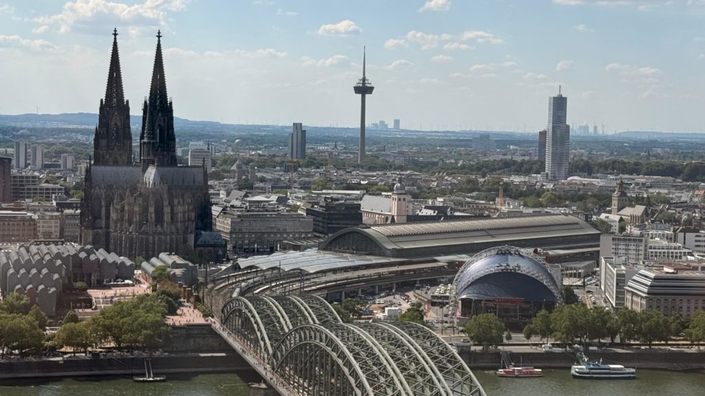 Ein wirklich sonniger und sehr heißer Tag. Weit weg wollten wir uns bei den Temperaturen nicht bewegen. Aber in unmittelbarer Nachtbarschaft unserer Herberge befindet sich ein Aussichtsturm, der „Cologne View“. Ein sehr schneller Fahrstuhl brachte uns in die 28. Etage und wir hatten einen
wunderbaren Blick auf den Rhein und ganz Köln. Wir konnten diesen Moment wirklich genießen und entschieden uns noch an dieser Aussichtsstelle zu verweilen.
